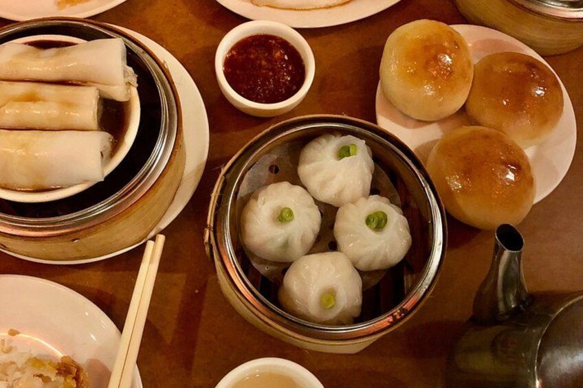 Een tafel met verschillende Aziatische gerechten, zoals loempia's, dumplings en broodjes. 3