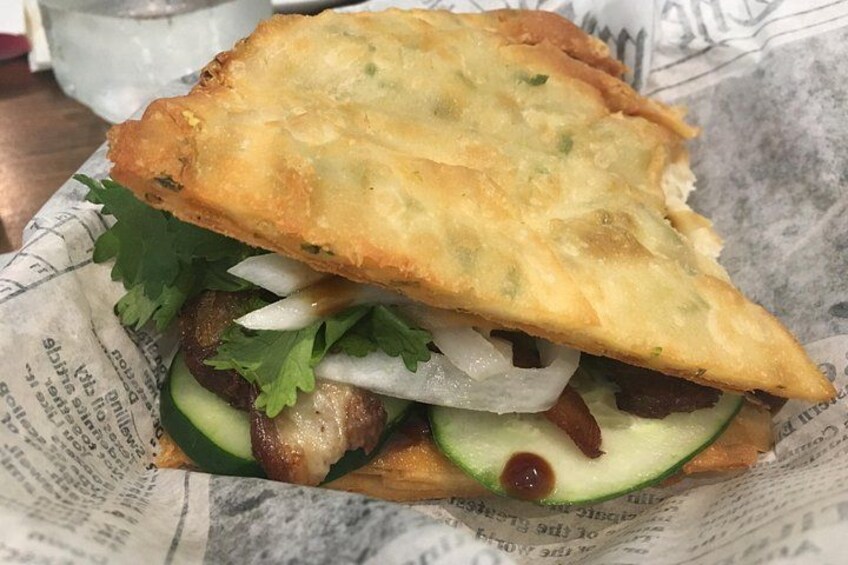 Een sandwich met een knapperige paneerlaag, sla, gesneden uien en komkommer. 4