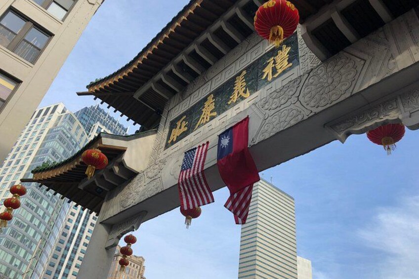 Een traditionele Chinese toegangspoort versierd met vlaggen, waaronder de Amerikaanse vlag en een vlag met een blauwe ster. 2