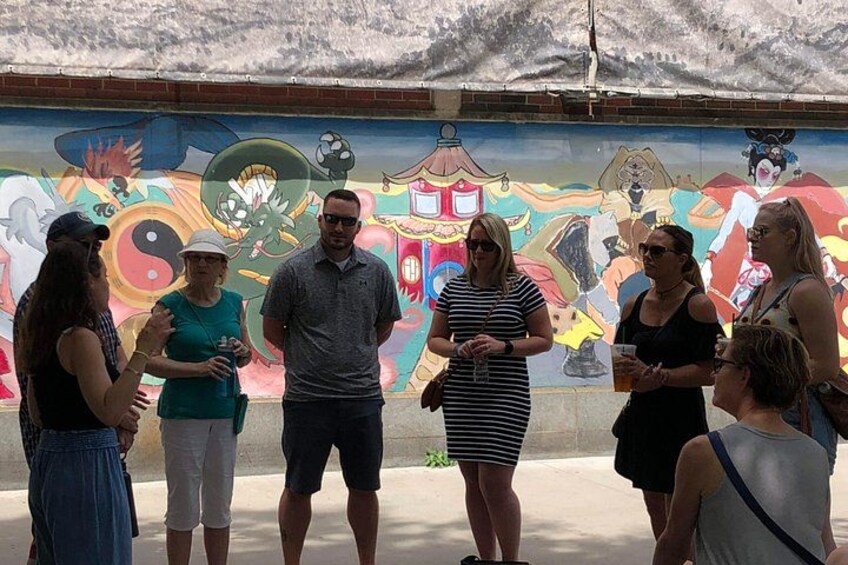 A group of people standing in front of a colorful mural. 2
