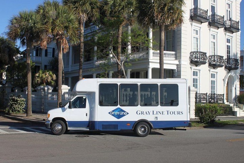A white tour bus with 'Gray Line Tours' on the side parked on a street. 1