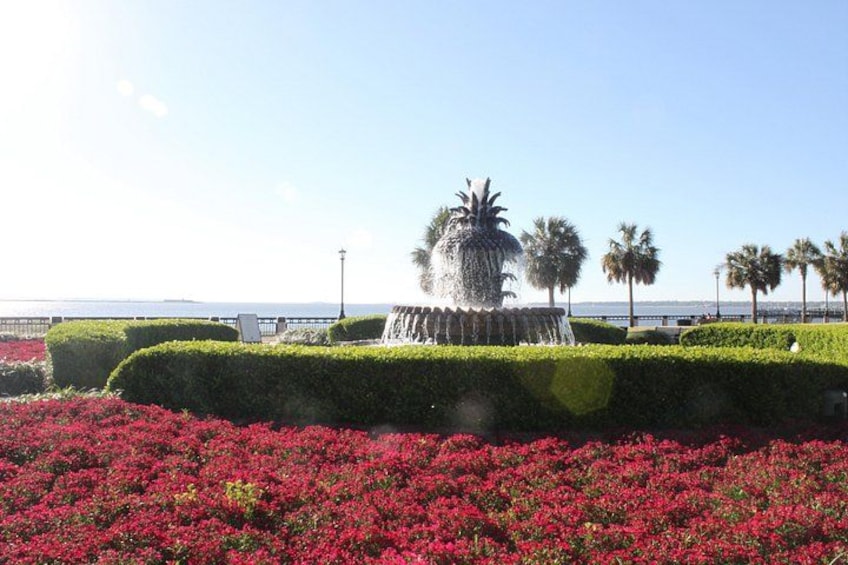 A fountain, palm trees, and red flowers. 2