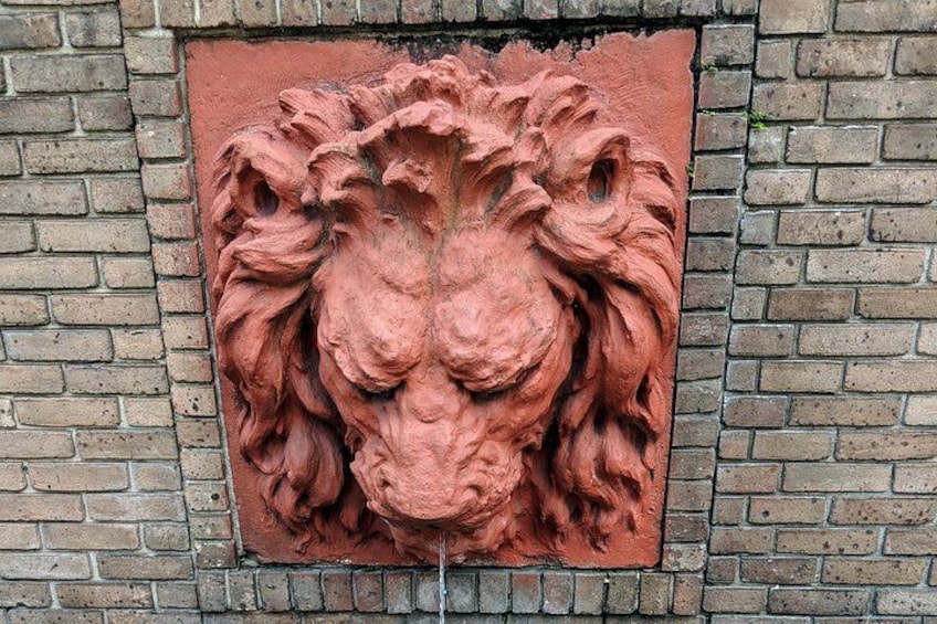 A red lion head sculpture mounted on a brick wall. 3