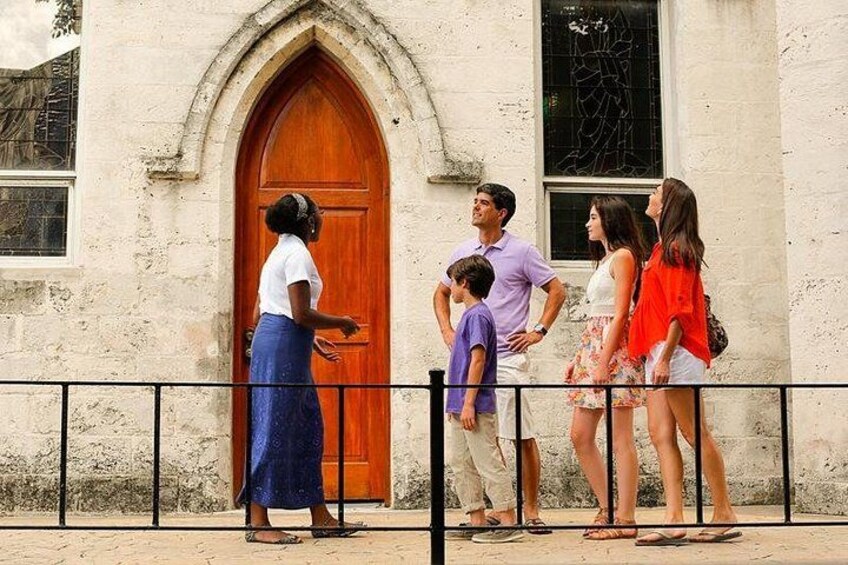 A group of people standing in front of a building with a large wooden door. 2