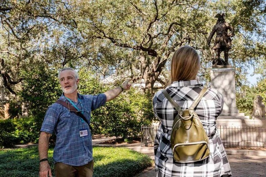 A man and a woman in a park, pointing at a statue. 2