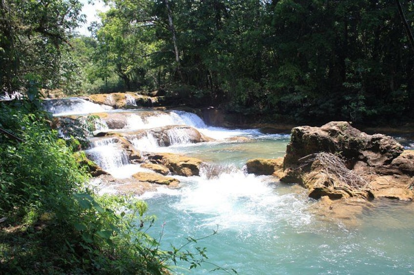 A waterfall cascading over rocks in a forested area. 4