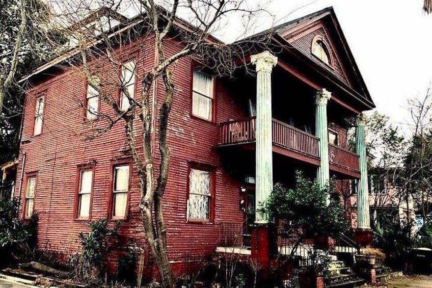 Ein rotes Backsteinhaus mit Balkon und Säulen. 2