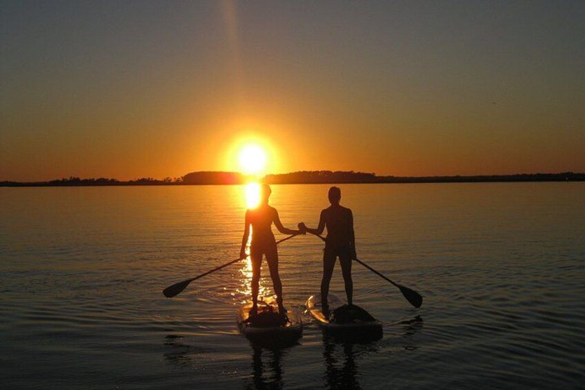 Deux personnes pratiquent le paddle sur une eau calme, au coucher du soleil. 5