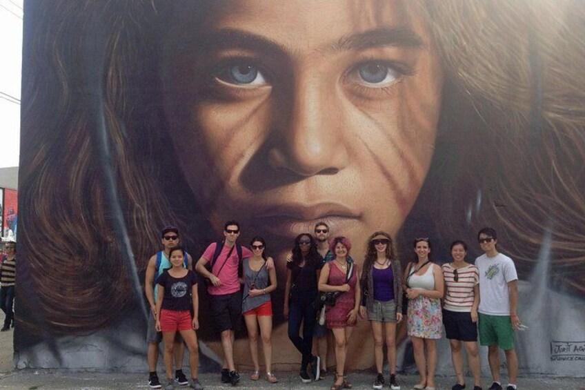 A group of people standing in front of a large mural. 4
