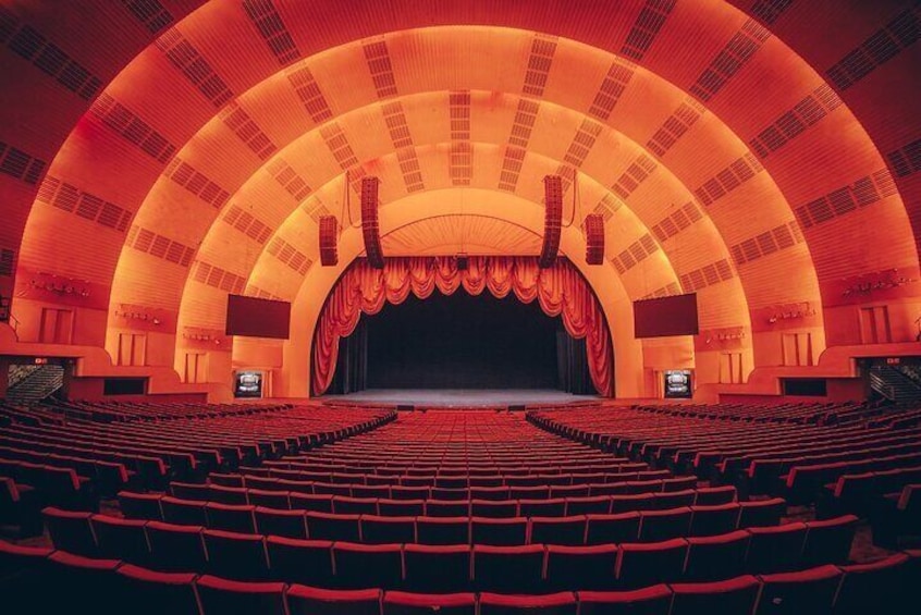 A large, empty theater with red seats and a stage. 2