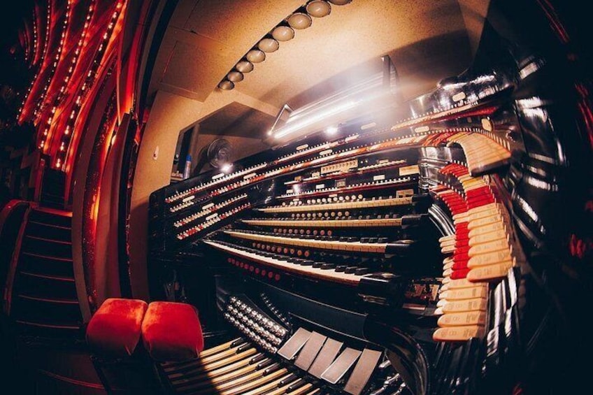 A grand piano with a red bench and a curved wall with lights. 4