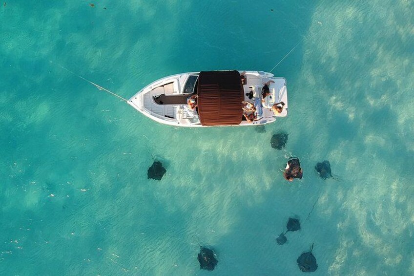 A small boat with people on a turquoise sea, anchored with a rope. 1