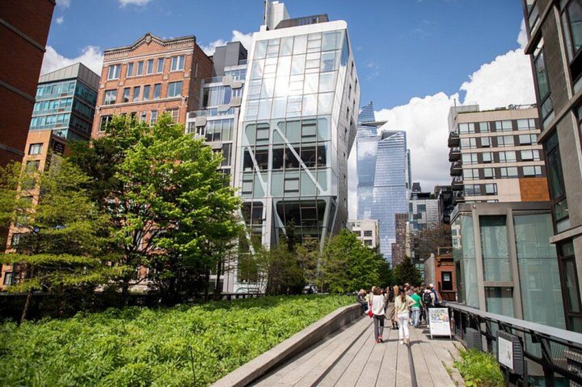 A city street with modern buildings, a wooden boardwalk, and pedestrians. 2