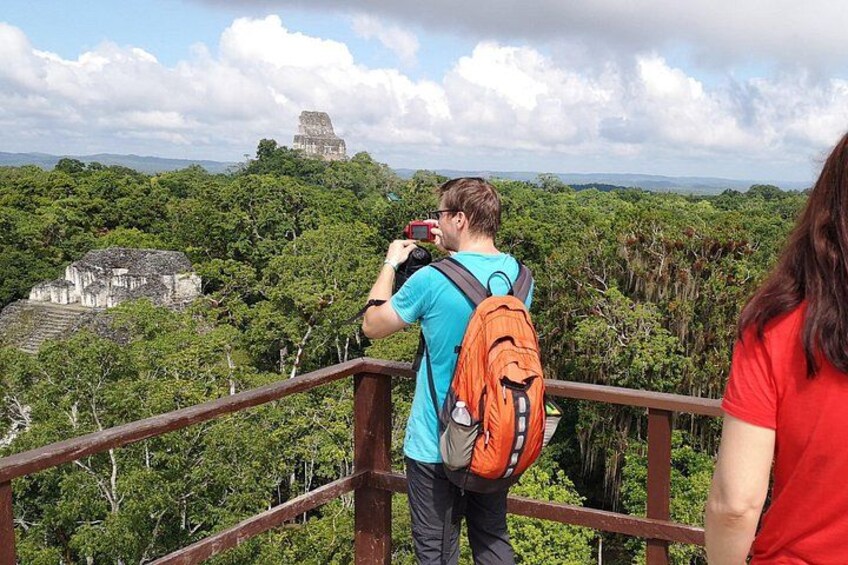 En person fotograferer en maya-pyramide med et skovlandskab i baggrunden. 5