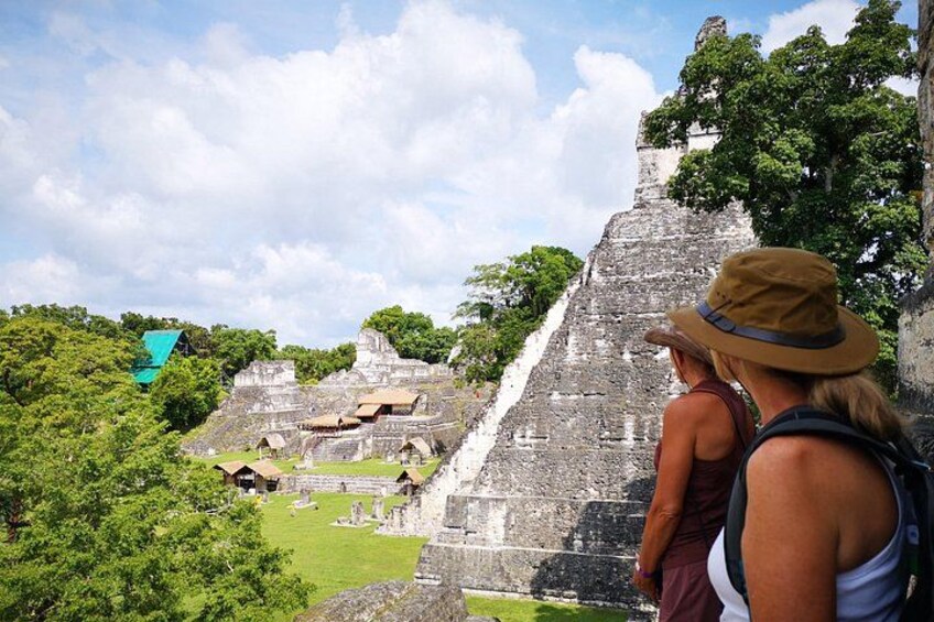 En stor, gammel pyramide med en mindre struktur i forgrunden, omgivet af frodig vegetation. 4