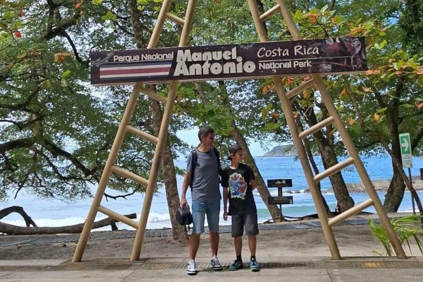 En skylt för nationalparken Manuel Antonio, med en strand och havet i bakgrunden. 5