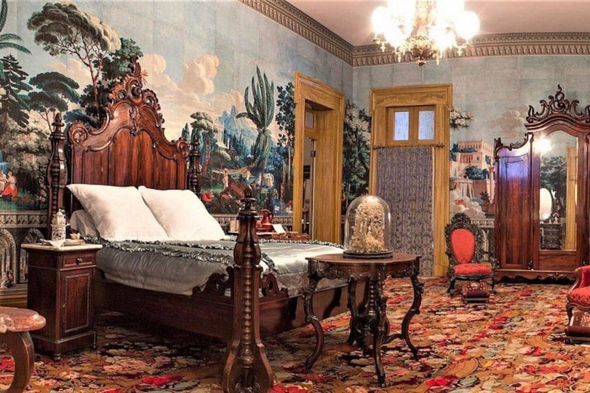 A bedroom with a large bed, ornate furniture, and a mural on the wall. 4