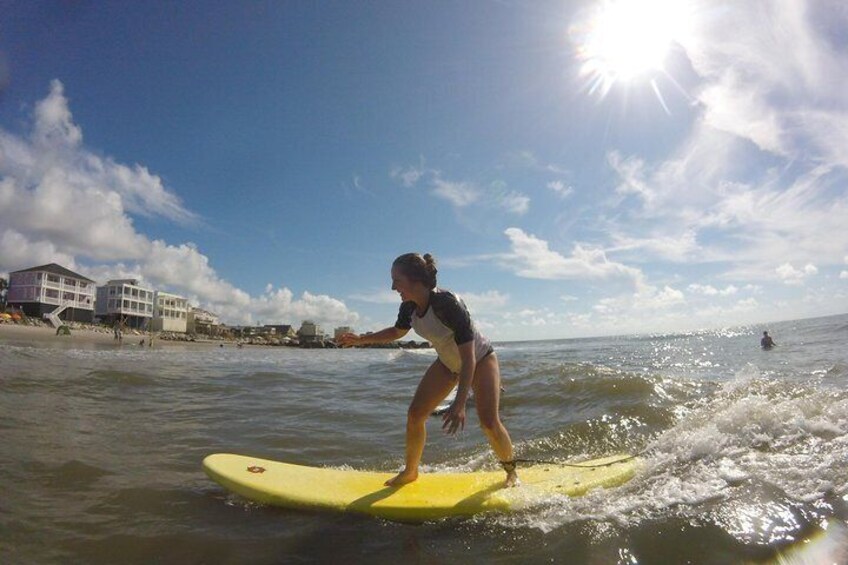Una persona surfeando sobre una tabla amarilla en el océano, con edificios al fondo. 5
