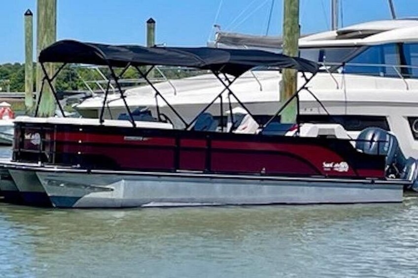 A red and white boat docked at a marina with a covered area and wooden pilings in the background. 3
