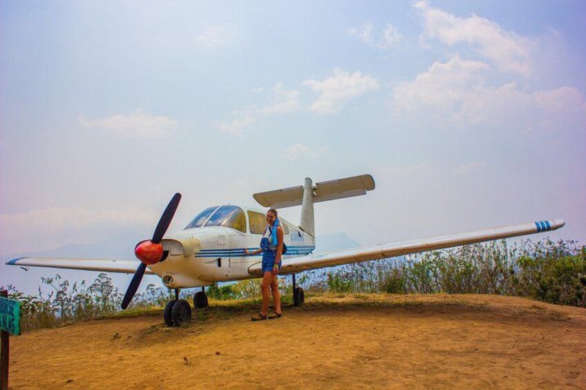 Un petit avion se trouve sur un terrain en terre, et une personne se tient à côté. 4