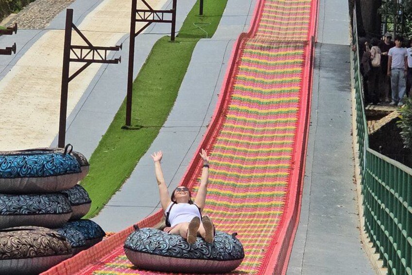 Une personne descend un toboggan coloré, et des coussins à motifs se trouvent en bas. 5