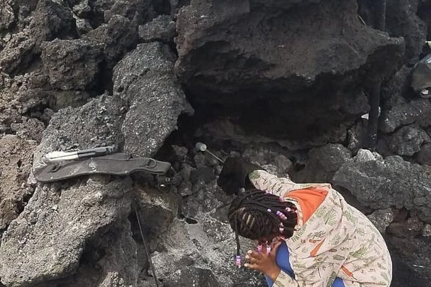 A person in camouflage attire near a rocky terrain with a metal object and a small hole. 3