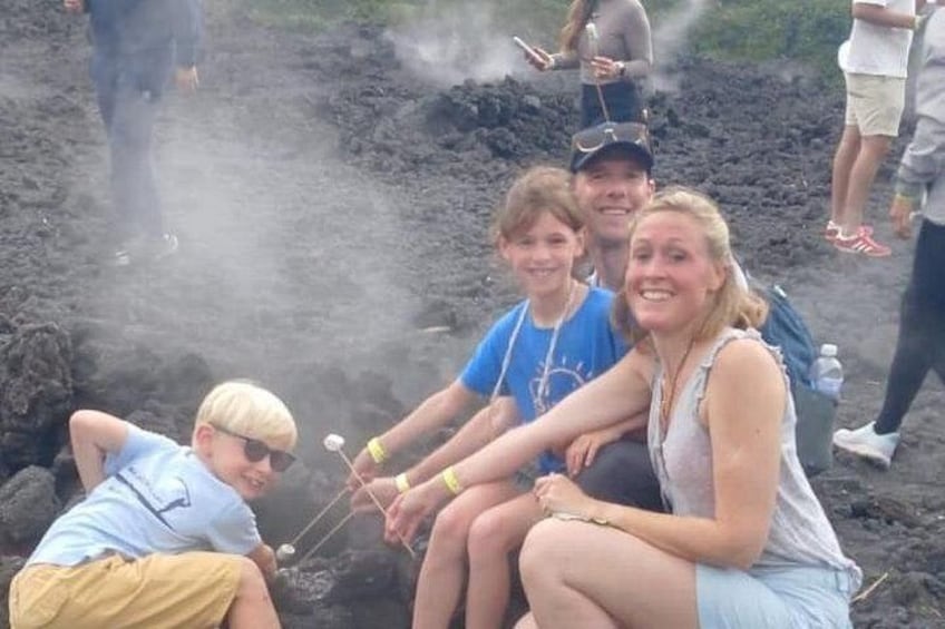 People sitting around a campfire, some holding marshmallows. 1