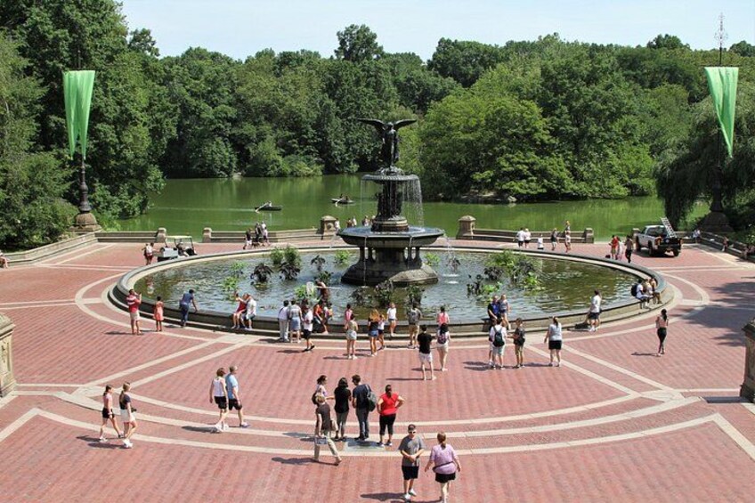 Un parc avec une fontaine centrale, un lac et des gens qui se promènent. 2