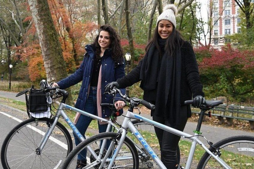 Deux personnes se tiennent debout, à côté de vélos, dans un parc où les arbres arborent les couleurs de l’automne. 3