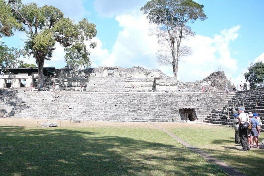 A historical stone structure with ruins, a grassy area, and a few people. 4
