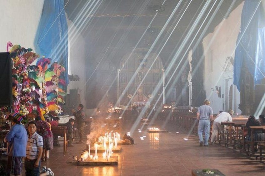 A church interior with a central aisle, candles, and people. 1