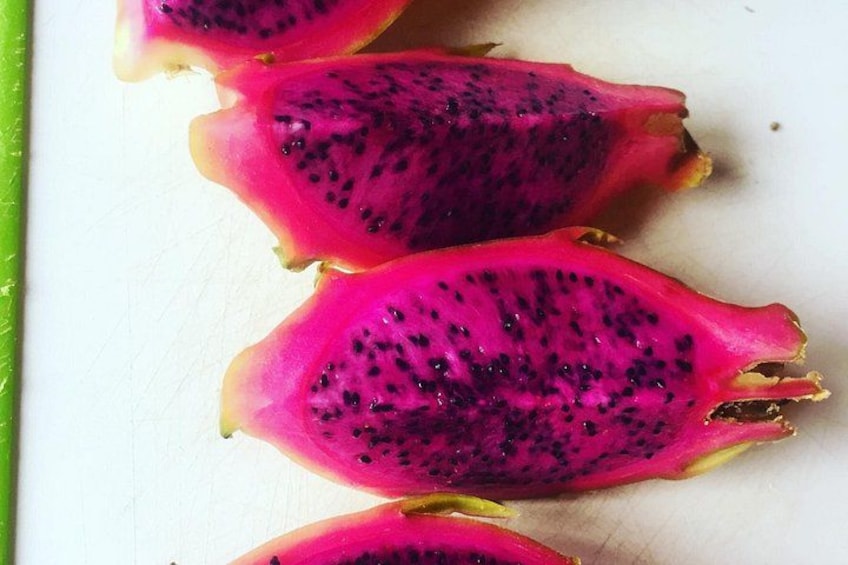 A dragon fruit cut in half, with pink flesh and black seeds. 3