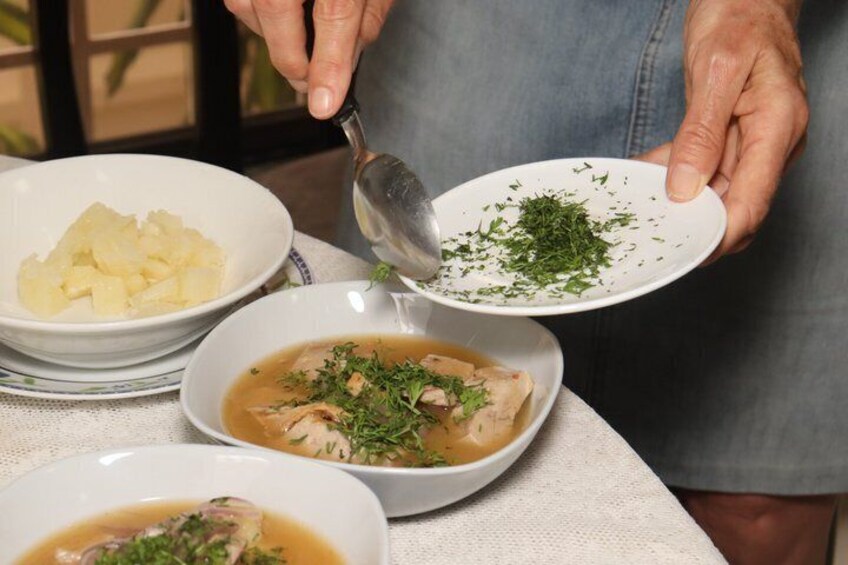 Una persona condimentando un tazón de sopa con hierbas. 2
