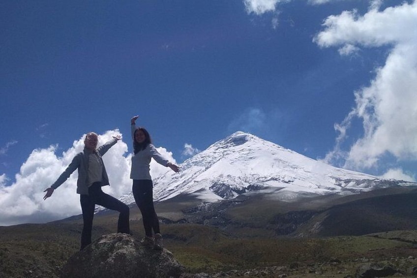 Two people standing on a grassy hill with a snow-capped mountain in the background. 2