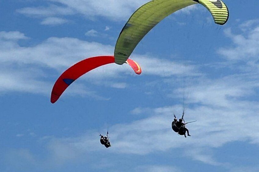 Tres parapentistas en el cielo, sobre un fondo azul claro. 3