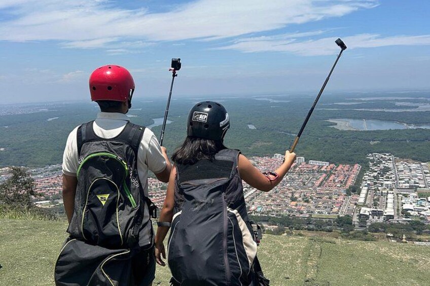Twee personen met selfie stokken maken een selfie op een heuvel met uitzicht op een stad. 4
