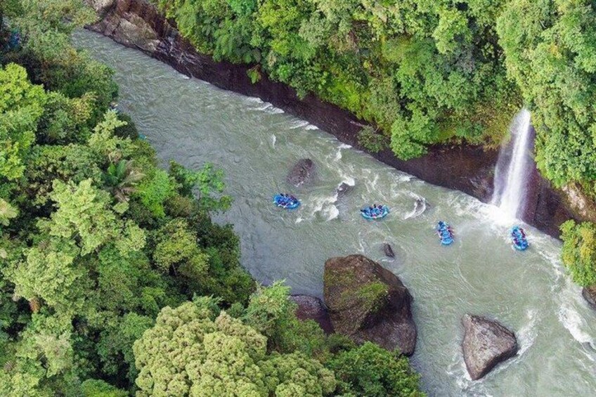 A river with rapids, surrounded by dense green foliage, and a waterfall. 2