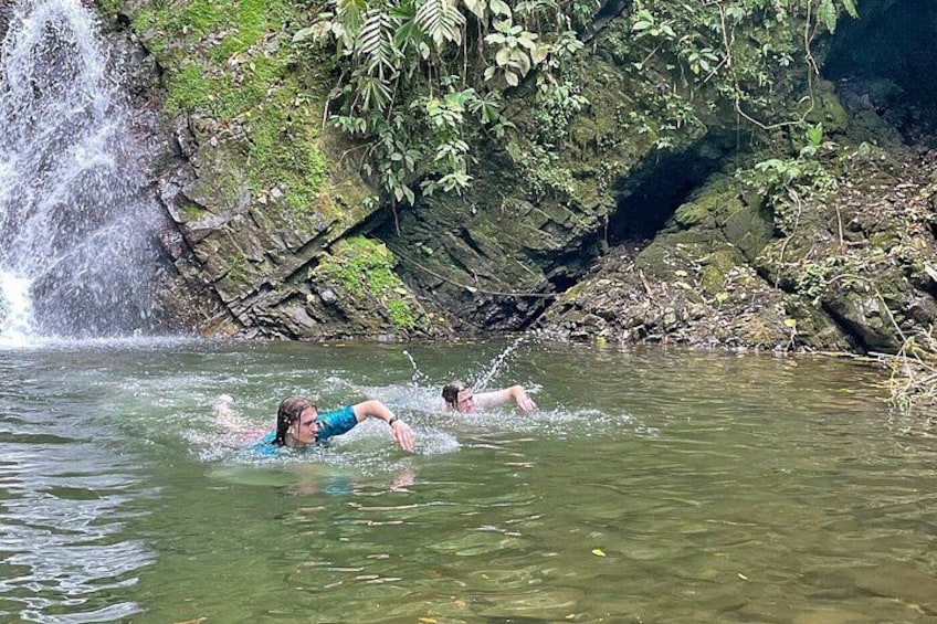 Dos personas nadando en una masa de agua natural con una cascada al fondo. 2