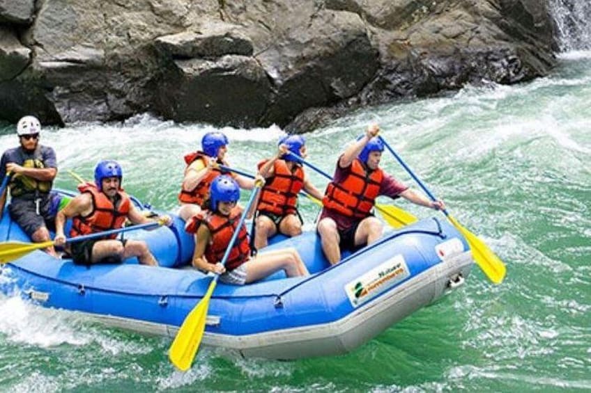 Un grupo de personas en una balsa inflable azul navegando por un río. 3