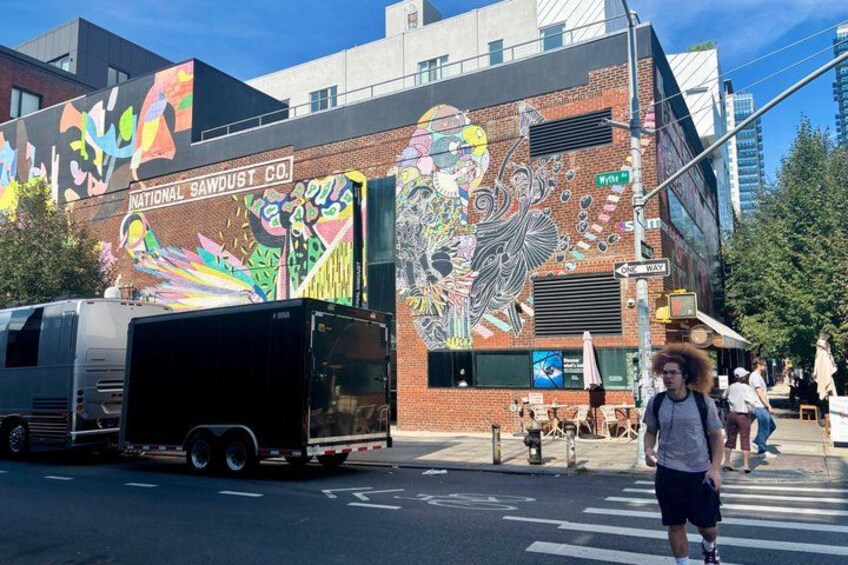 A mural on a building, a street with a crosswalk, and a parked trailer. 2