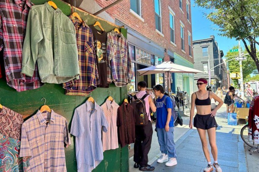 A street market with clothing stalls and pedestrians. 3