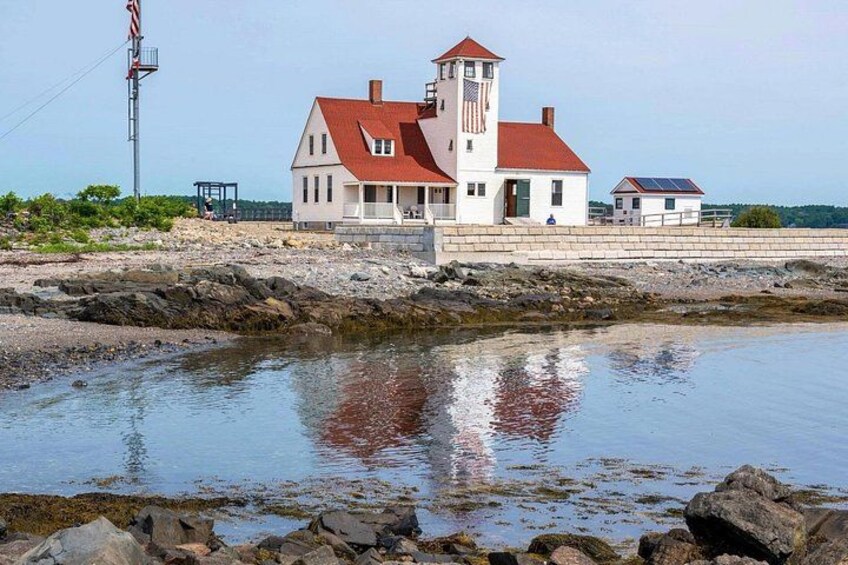 A coastal lighthouse with a red roof, a white tower, and a small adjacent building. 4