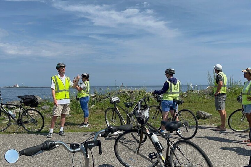 Un grupo de personas con chalecos de seguridad junto a una carretera costera y bicicletas. 5