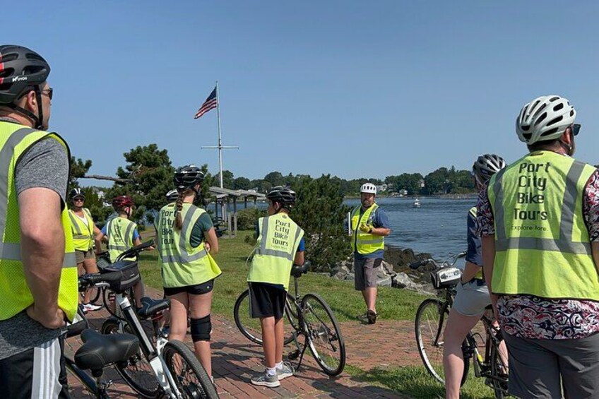 A group of people wearing safety vests and helmets by a waterfront. 3