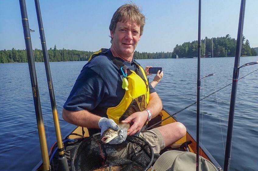 Une personne dans un canoë sur un lac, tenant des cannes à pêche. 2