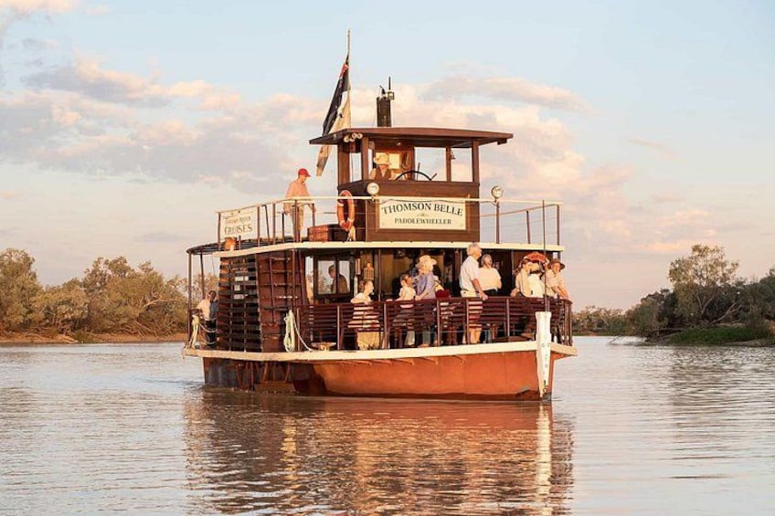 A boat named 'Thomson Belle' with passengers on deck, surrounded by calm water and trees. 5