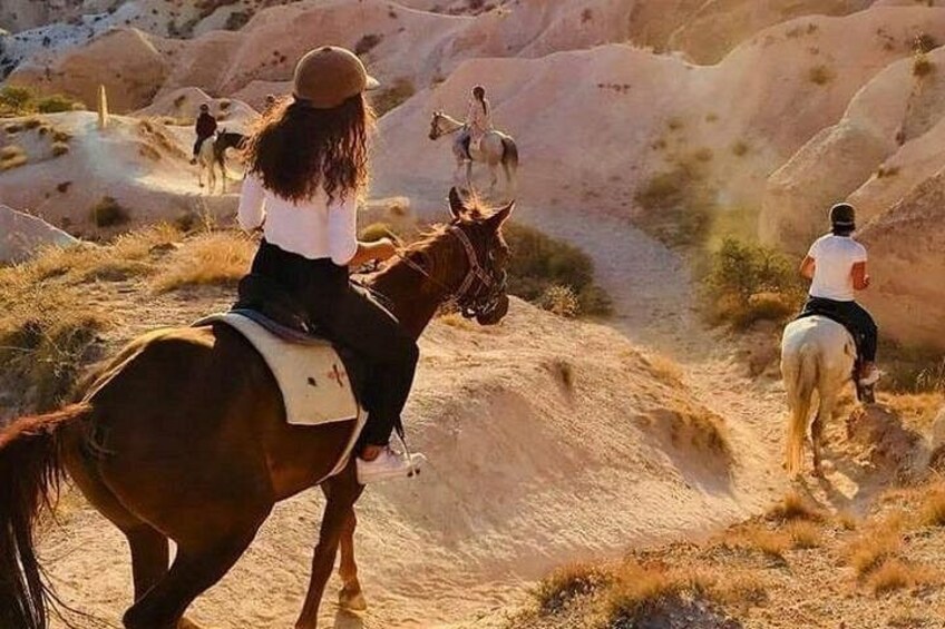 A person riding a horse on a dirt trail with a mountainous landscape in the background. 1
