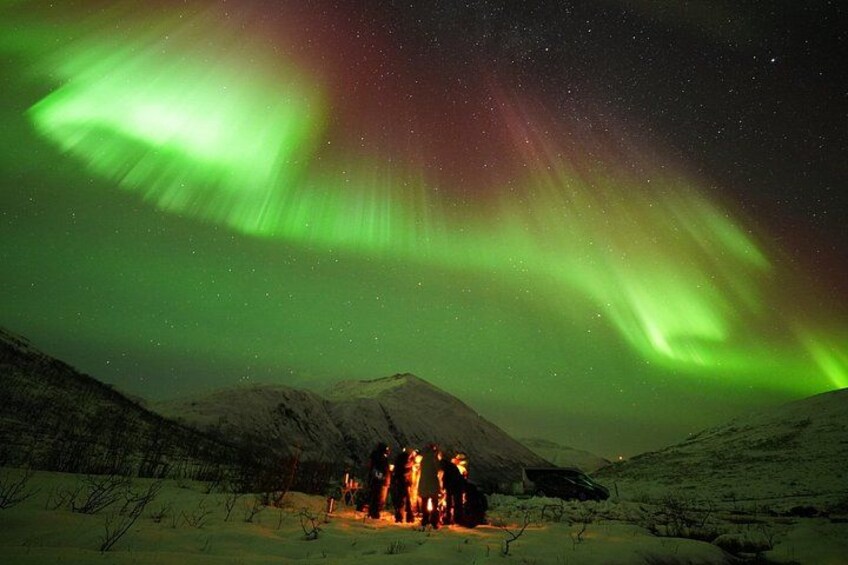 The Northern Lights over a snowy landscape with a lit cabin. 2
