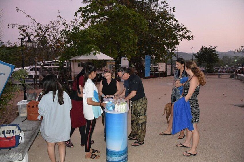 A group of people gathered around a blue barrel, possibly for a social event. 3
