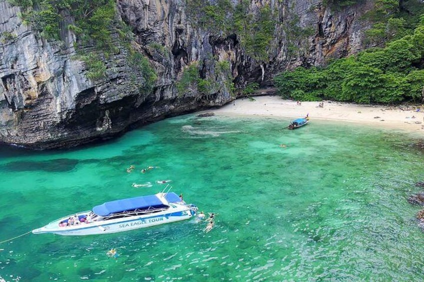 A boat named 'SEA EAGLE TOUR' anchored near a beach with clear turquoise water and rocky cliffs. 1